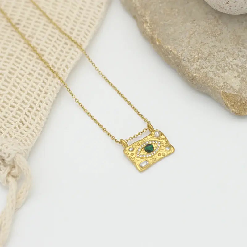 Collier pendentif doré rectangulaire martelé avec un oeil et serti d'une pierre verte et de diamants en zircon  blancs