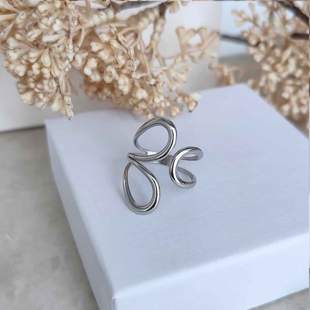 Bague femme originale en acier inoxydable argenté ajustable au design ouvert et aux lignes arrondies.