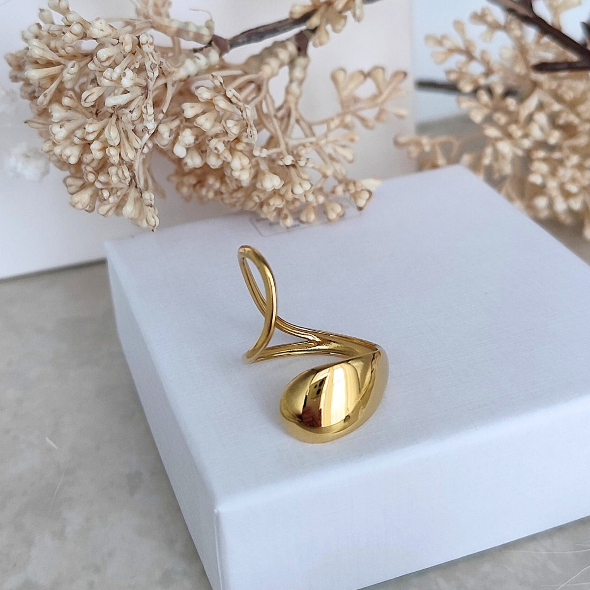 Bague ouverte devant dorée aux extrémitées de formes ovales qui se superposent 