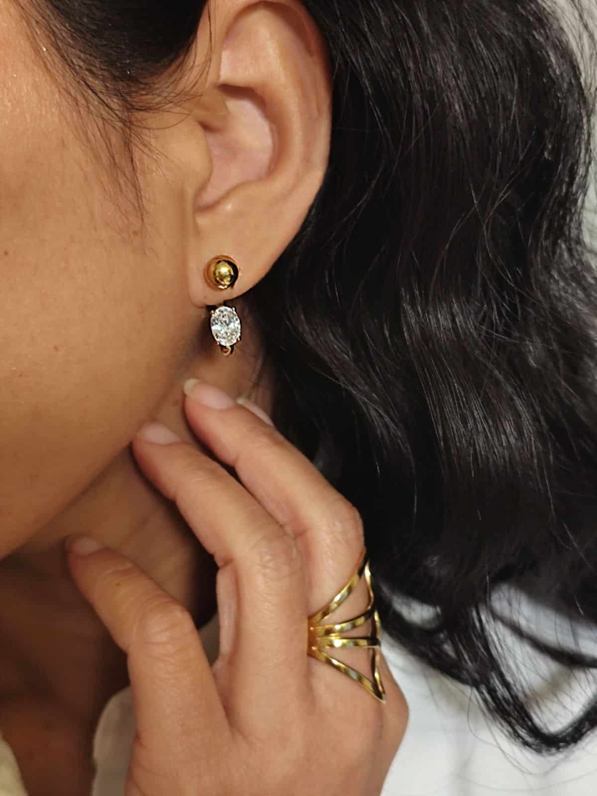 Boucles avec une boule au niveau du lobe et un anneau fin qui revient de derrière jusqu’à l’avant, serti d’un diamant portées à l'oreille