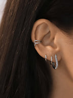 Ces clous d’oreilles en acier inoxydable de forme arrondie sertis de zircons portés en accumulation avec d'autres boucles argentées
