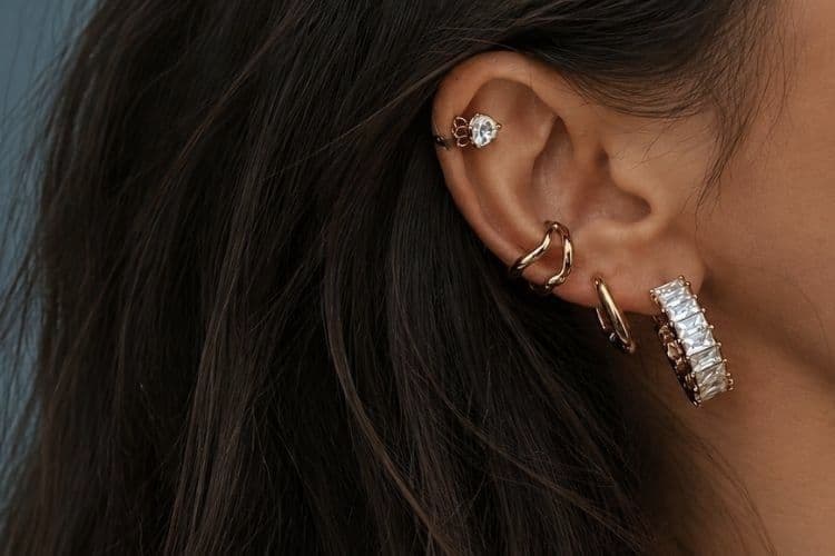 Gros plan d'une oreille portant plusieurs boucles d’oreilles en acier inoxydable