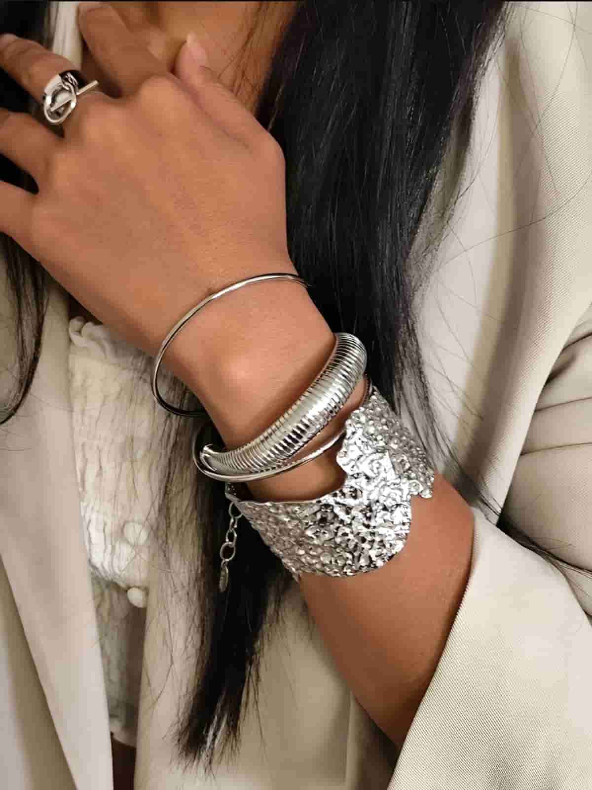 bracelets en acier inoxydable argentés portés en accumulation sur le poignet