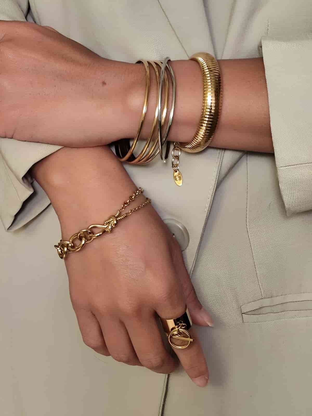 Bracelet en acier inoxydable 316L à maille serpent striée avec barre pivotante texturée doré porté en accumulation avec d'autres bracelets