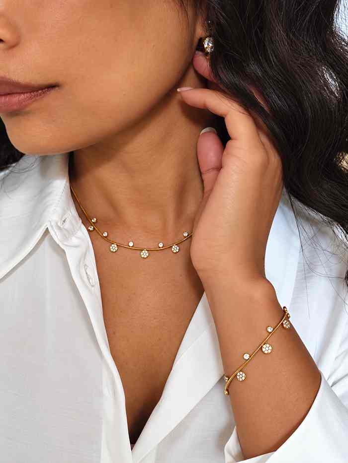 Ensemble Bracelet  et collier en acier inoxydable fin, doré avec de petits pendentifs alternés  porté sur le poignet, portés sur un modèle