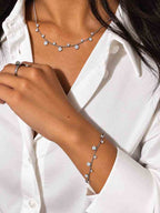 Bracelet en acier inoxydable fin, argenté avec de petits pendentifs en zircons et forme de fleur porté par un modèle