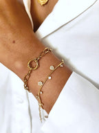 Bracelet en acier inoxydable fin, dorés avec de petits pendentifs en zircons et forme de fleur porté