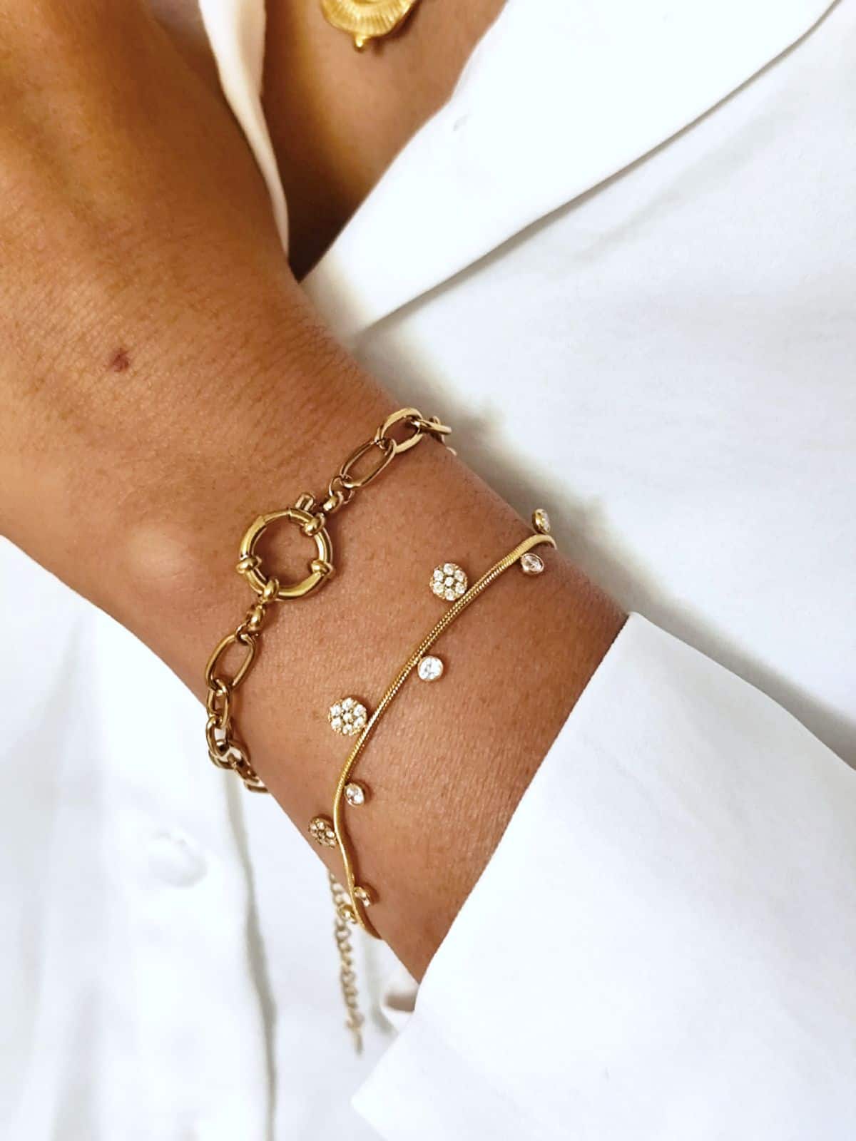 Bracelet en acier inoxydable fin, dorés avec de petits pendentifs en zircons et forme de fleur porté