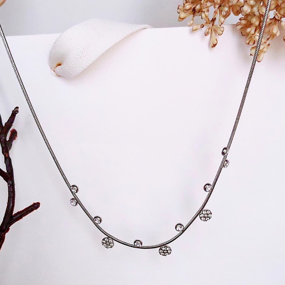 Collier ras de cou en acier inoxydable fin, argenté avec de petits pendentifs alternés 