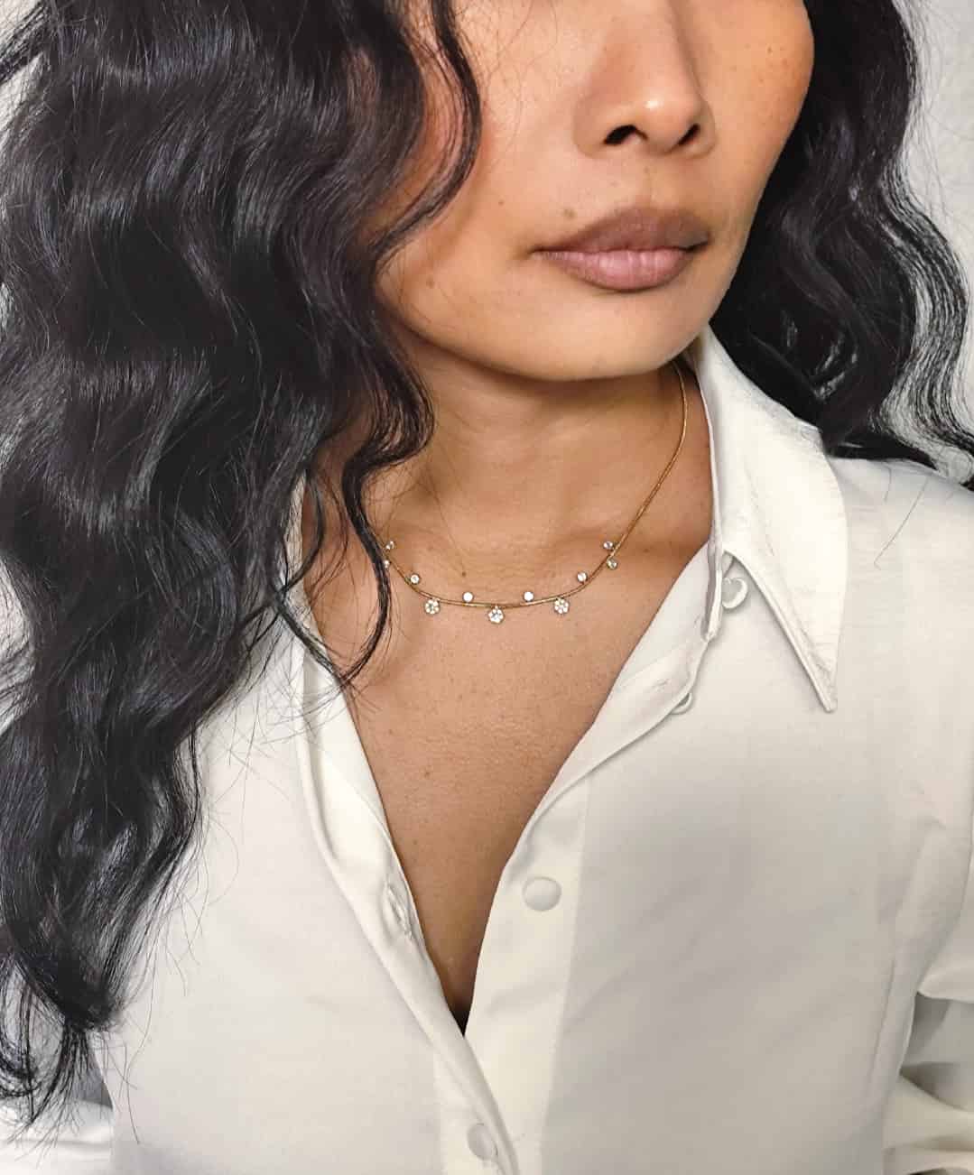 Collier ras de cou en acier inoxydable fin, dorés avec de petits pendentifs alternés  porté sur un modèle