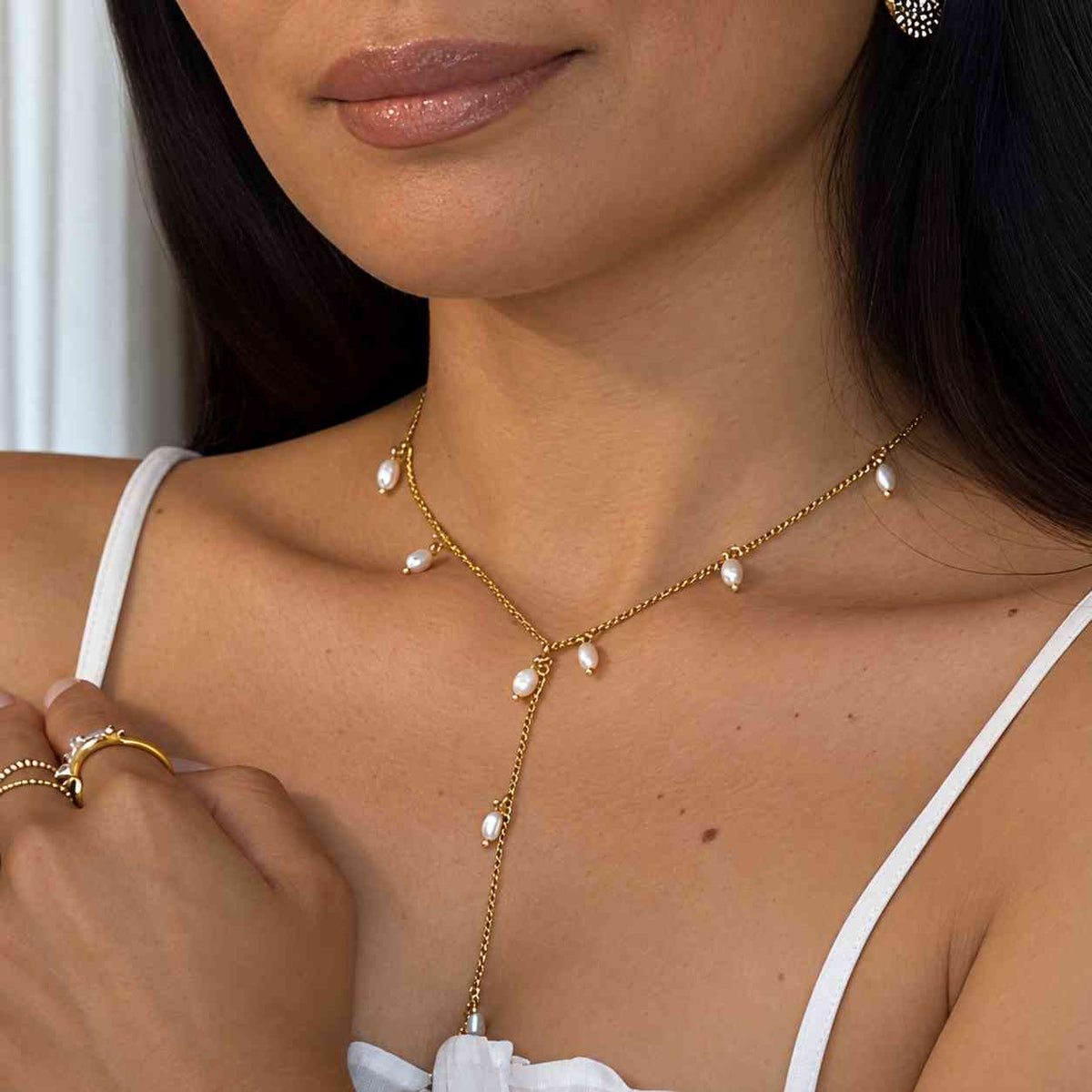 Collier doré porté sur un modèle en forme de Y au style Bohème chic parsemé de Perles de Coquillages blanches nacrées