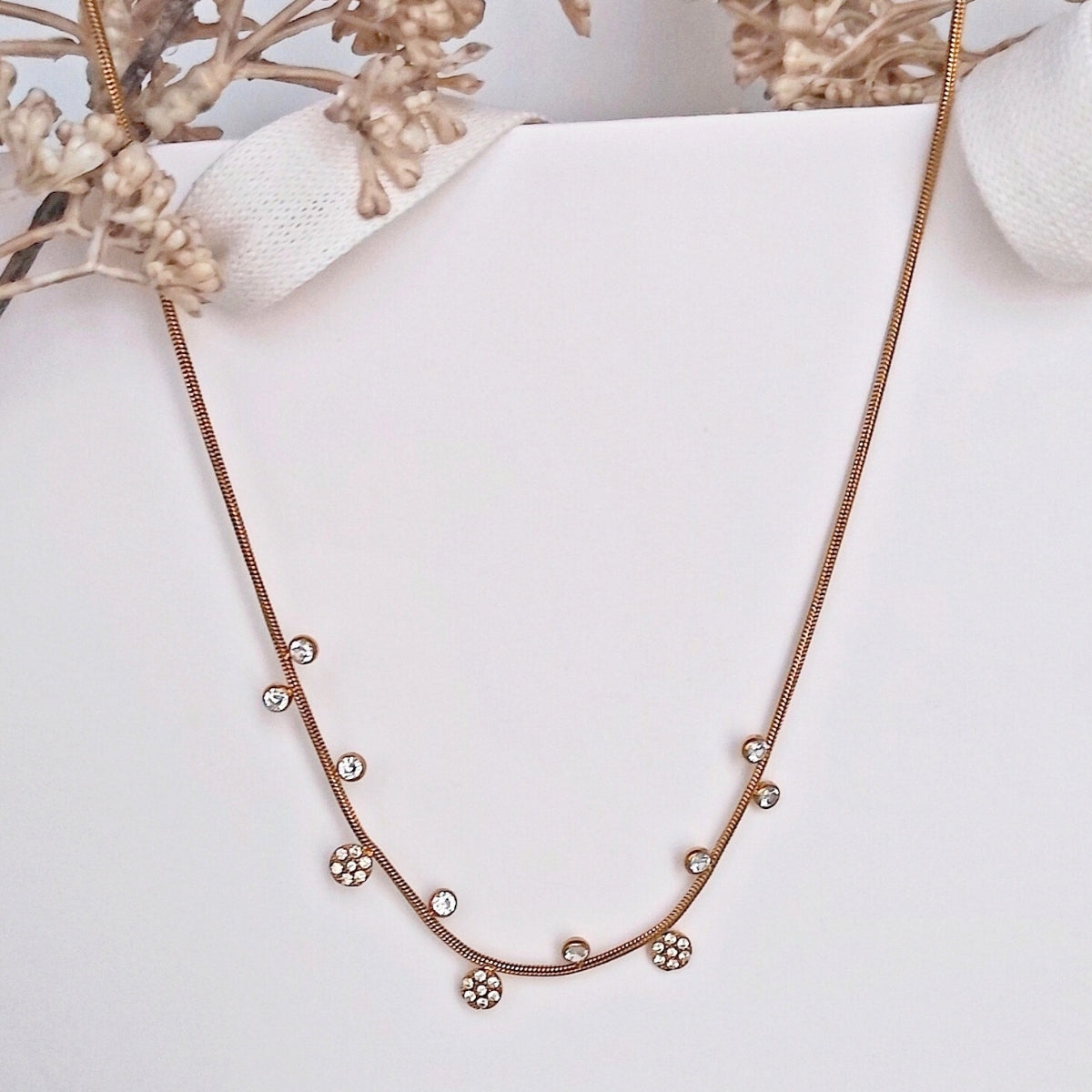 Collier ras de cou en acier inoxydable fin, doré avec de petits pendentifs alternés