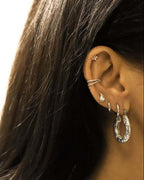 Boucles d'oreilles créoles martelées forme hexagone argentées en acier portées en accumulation avec d'autres boucles