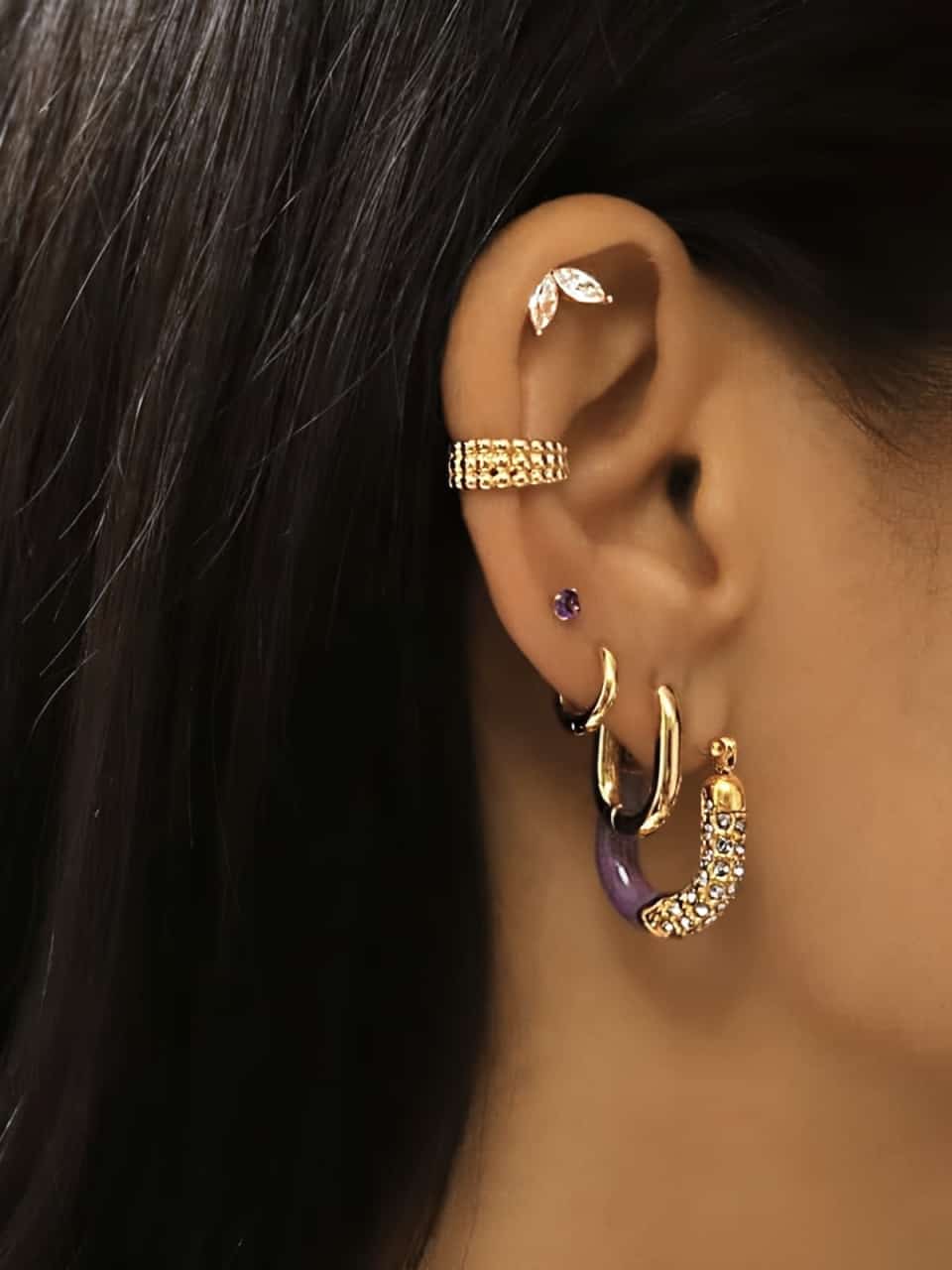 Ces petites créoles ovales en acier inoxydable dorées portées avec d'autres boucles