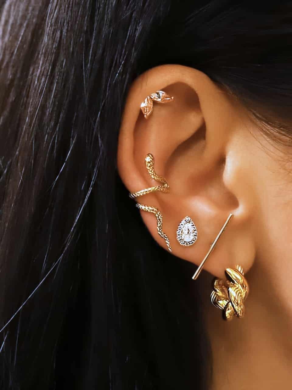 Petites créoles dorées torsadées en acier inoxydable portées en accumulation avec d'autres boucles