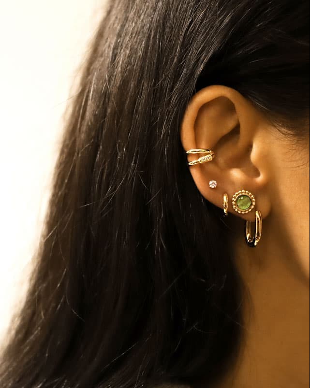Puces d'oreilles rondes serties d'une Pierre Oeil de Chat verte dorées en acier inoxydable portée en accumulation avec d'autres boucles d'oreilles