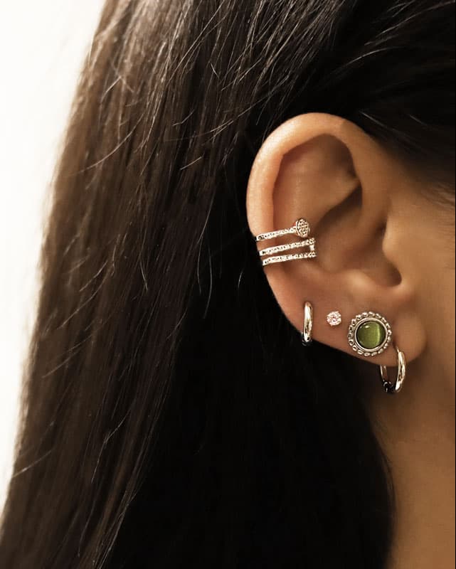 Puces d'oreilles rondes serties d'une Pierre Oeil de Chat verte argentées en acier inoxydable portées en accumulation avec d'autres boucles d'oreilles